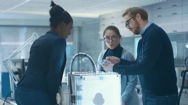 Three Very Bright and Young Multiethnic Students Discussing 3D Printed Mechanism in a New Modern Laboratory. — Stock Video