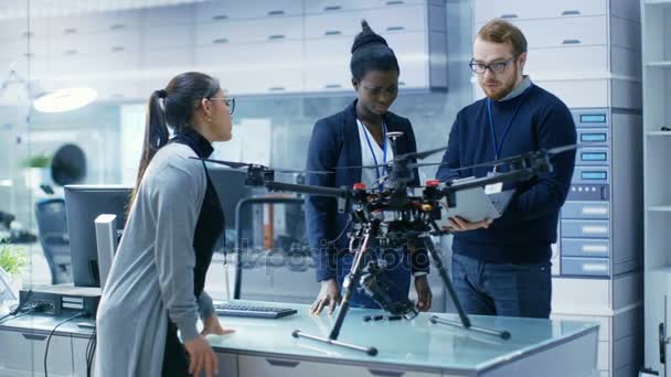 Multietnické tým mladých ženských a mužských inženýrů pracuje na prototyp moderní DRONY. Jsou v laboratoři světlé High-Tech. — Stock video