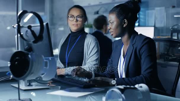 Μαύρο και Καυκάσου γυναίκες επιστήμονες που εργάζονται σε έναν υπολογιστή, συσχετίζοντας τις σημειώσεις και την εμπειρία τους. Εργάζονται σε ένα σύγχρονο εργαστήριο / ερευνητικό κέντρο. — Αρχείο Βίντεο