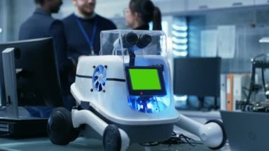 Çok etnik grup genç ve parlak erkek ve kadın bilim adamları dostça tartışma gayri resmi bir atmosfere sahip. Büyük Modern laboratuvar / araştırma merkezi var Robot ile yeşil Mock-up perde.