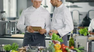 İki ünlü şefler Exchange fikirler hakkında Video Blog reçete onlar tablete izliyor. Onlar büyük restoran mutfağında çalışan.