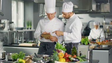 İki ünlü şefler kendi Video Blog kullanarak Tablet bilgisayar süre tartışmak. Onlar büyük restoran paslanmaz çelik profesyonel mutfağında çalışması.
