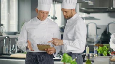 İki ünlü şefler Exchange fikirler hakkında Video Blog reçete onlar tablete izliyor. Onlar büyük restoran mutfağında çalışan.