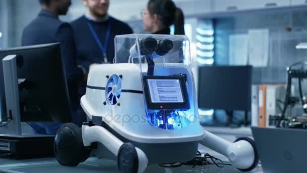 Groupe multiethnique de scientifiques jeunes et brillants, hommes et femmes, discutent amicalement dans l'atmosphère informelle. Ils travaillent dans un laboratoire / centre de recherche moderne Création de robotique .