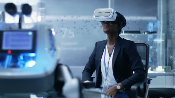Ung sort kvindelig virtuel virkelighed ingeniør / udvikler iført VR headset skaber indhold. Hun er alene i et moderne laboratorium / forskningscenter . – Stock-video