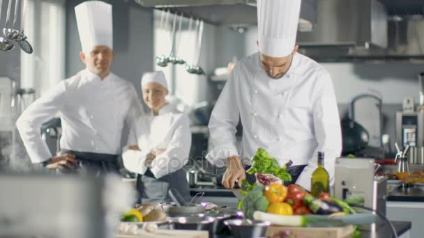 O famoso chef de um restaurante grande cruza braços e sorrisos em uma cozinha moderna. Sua equipe em sorrir no fundo . — Vídeo de Stock