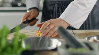 Bir şef ustaca kesme renkli sebze kesme tahtası ve onları kaynar tencerenin içine koyarak Close-Up.