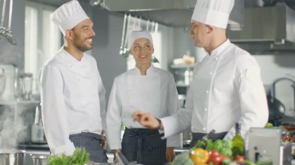 In der modernen Küche Mitarbeiter diskutieren mit Koch. Küche ist voll von Lebensmittelzutaten, Gemüse, Fleisch, kochender Suppe. — Stockvideo