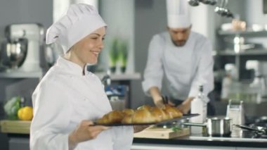 Bayan Baker tepsiyi taze pişmiş kruvasanlar ile taşır.