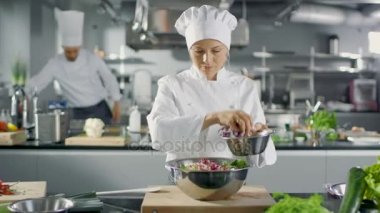 Ünlü bir restoranda kadın aşçı salatası hazırlar. O büyük bir Modern mutfakta çalışıyor.