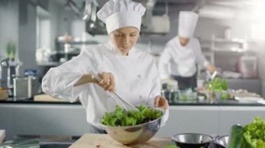 Ünlü bir restoranda kadın aşçı salatası hazırlar. O büyük bir Modern mutfakta çalışıyor.