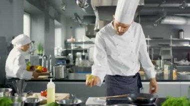 Profesyonel Chef sıkar limon suyu ile kırmızı balık fileto üzerine sıcak tava üzerine. O bir Modern mutfakta çalışıyor.