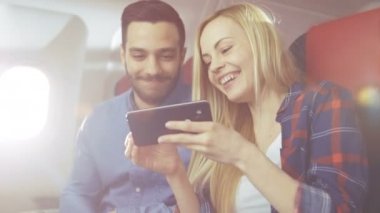 Güzel genç sarışın yakışıklı İspanyol erkek oynamak ile onların tatil uçuş Smartphone ile. Yeni ticari uçak iç görünür olduğunu.