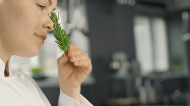 Hermosa joven hembra chef huele planta de especias decorativas . — Vídeo de stock