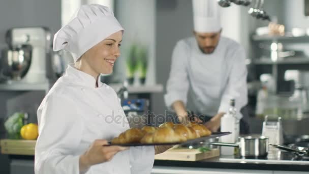 Baker femelle porte plateau avec des croissants fraîchement cuits au four . — Video