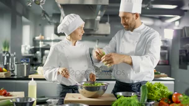 Des chefs célèbres masculins et féminins préparent une salade pour leur restaurant cinq étoiles. Ils travaillent sur une grande cuisine professionnelle en acier inoxydable de restaurant . — Video