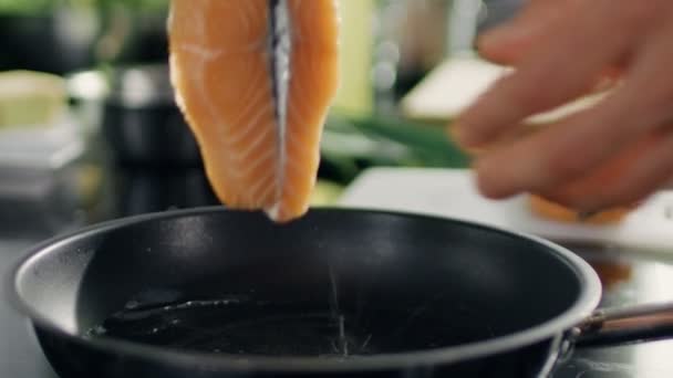 Primer plano de manos poniendo filete de pescado rojo en una sartén caliente . — Vídeos de Stock