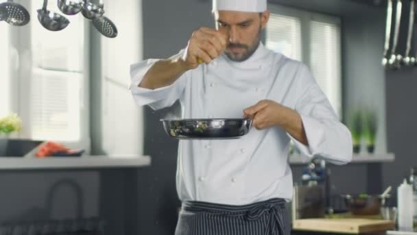 El chef profesional exprime jugo de limón en la sartén caliente con filete de pescado rojo. Trabaja en una cocina moderna . — Vídeo de stock