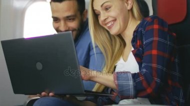 Mutlu çift transatlantik uçuş seyretmek film üstünde onların Laptop üzerinde. Güzel sarışın kız ve onun Hispanik erkek mutlu birlikte misiniz.