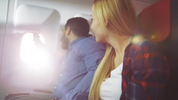 On a Commercial Plane Handsome Young Hispanic Male Opens Window's Shade and Hugs His Beautiful Blonde Girlfriend and they Romantically Look Through the Window. Sun Shines through the Porthole. — Stock Video