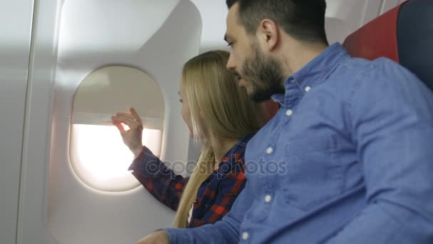 Σε μια πτήση εμπορικό αεροπλάνο όμορφη ξανθιά επιβάτης ανοίγει παράθυρο σκιά και ξυπνά ύπνου Ισπανόφωνος αρσενικό γείτονά της. Νέο αεροπλάνο έχει όμορφα σχεδιασμένο εσωτερικό. — Αρχείο Βίντεο