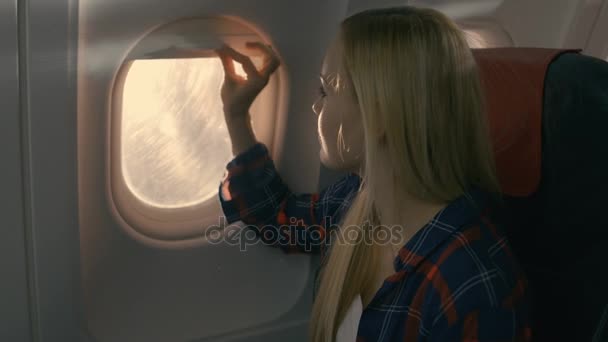 Bir uçak güzel sarışın kız açar gölge ve pencereden dışarı görünüyor. Sun Shining onu ve o gülümsüyor üzerinde olduğunu.
