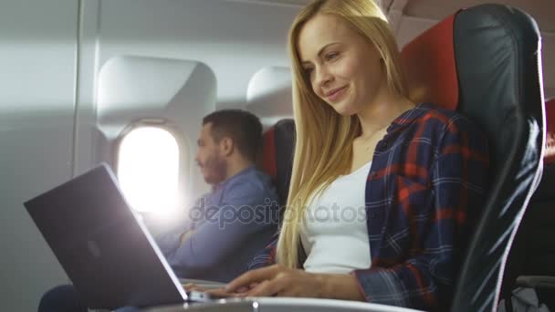 On Board of Commercial Airplane Beautiful Young Blonde Works on a Laptop while Her Hispanic Male Neighbor Sleeps. — Stok Video