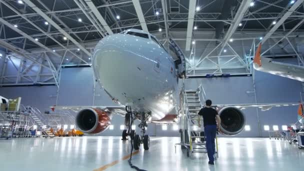  Značka nové letadlo stojící v hangáru údržby letadel během údržby letadel inženýr / technik / mechanik jde uvnitř kabiny přes žebřík / rampa. 