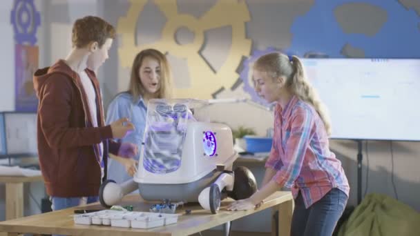 Twee meisjes en een jongen inschakelen volledig functionele geprogrammeerde Robot met Bright Led verlichting voor klassenproject van de wetenschap van de School. — Stockvideo