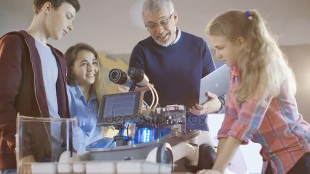 El maestro y sus alumnos trabajan en un robot programable con iluminación led para el proyecto de clase de ciencias escolares . — Vídeo de stock