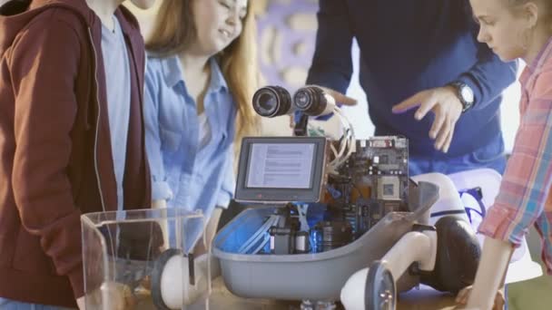 Lärare och hans elever arbeta på en programmerbar Robot med Led belysning för vetenskap klass skolprojekt. — Stockvideo