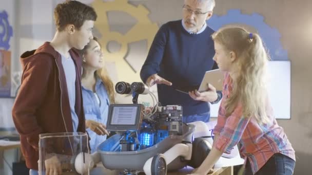 Учитель и его ученики работают над программируемым роботом с светодиодной подсветкой для проекта школьного научного класса . — стоковое видео