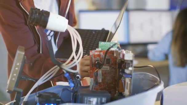 Хлопчик будує повністю функціональний робот з яскравими світлодіодними ліхтарями та програмує його з ноутбуком для проекту Його шкільного клубу робототехніки . — стокове відео