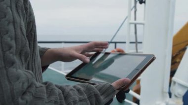 Koruyucu kat balıkçı Tablet bilgisayar kullanarak navigasyon haritaları gemide seyahat ederken giymiş.