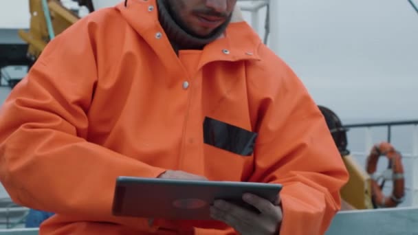 Lässig gekleideter Fischer mit Tablet-Computer mit Navigationskarten auf dem Schiff. — Stockvideo