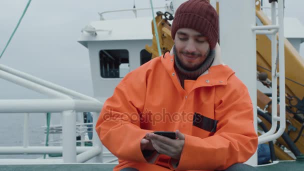 Casualy を着て漁師を使用して携帯電話の船で旅をしながら. — ストック動画