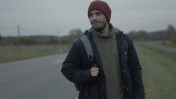 Casualy klädda Traveler promenader längs motorvägen på en molnig dag. — Stockvideo