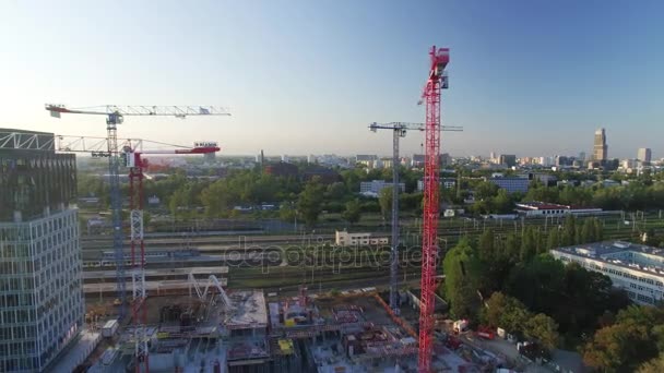 Tiro aéreo de guindastes em um canteiro de obras. Grande paisagem urbana é visível na luz do sol . — Vídeo de Stock