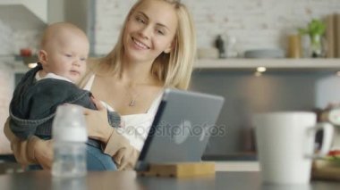 Mutfak anne bebeğini tutar. Her ikisi de bir Tablet bilgisayar ekranında ilginç bir şey bakmak.