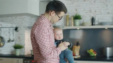 Mutfak genç Baba onun bebek tutar. O bir bebek onun el verir ve bebek onun içinde Clenches.