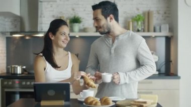 Yakışıklı iki Tablet tablo ile mutfakta. Kruvasan o içecekler kahve yediği.