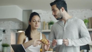 Yakışıklı iki Tablet tablo ile mutfakta. Kruvasan o içecekler kahve yediği.