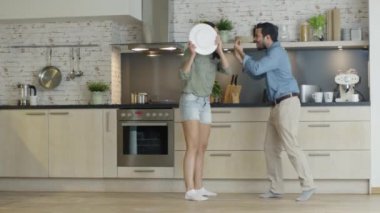 Genç kavgalar mutfak çift. Kız yeterli ve plaka tatili. Adam hayal kırıklığı içinde çığlık atıyor ve öfkeyle Gesticulates. Ağır çekim.