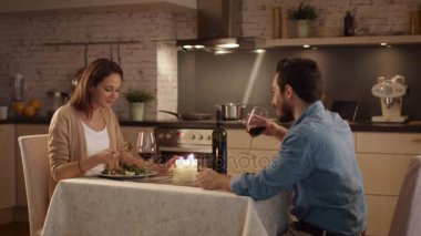Güzel çift mutfakta mum ışığında akşam yemeği. Şarap içiyorlar yemek ve konuşmak. Her ikisi de gülümseme ve iyi ruh halinde.