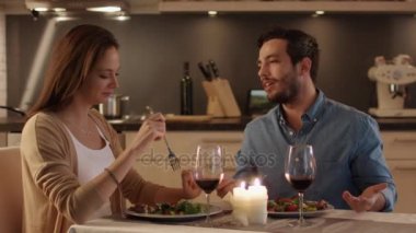 Güzel çift mutfakta mum ışığında akşam yemeği. Yemek, içmek ve konuşmak. Her ikisi are iyi durumda ve çok gülümseme. Slom hareket.
