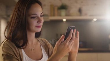 Güzel kız kullanır mutfakta otururken Smartphone. Gülen kız.