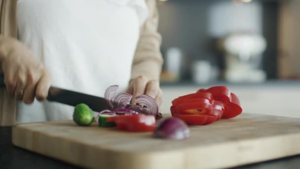 Nahaufnahme, in der zarte Frauenhände Gemüse auf dem Küchentisch schneiden. — Stockvideo