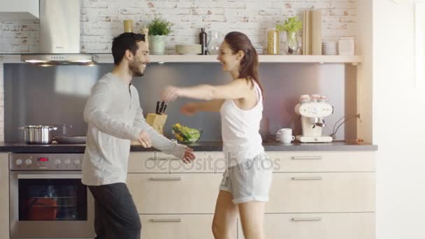 Jovem casal dança na cozinha, em seguida, menina flerte salta nos braços do homem . — Vídeo de Stock