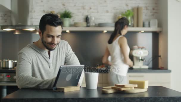 Pár v kuchyni. Kuchaři žena, zatímco muž používá Tablet. — Stock video