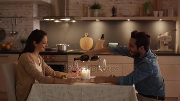 Junges Paar beim Abendessen bei Kerzenschein. Reden. Mann schüttet Wein in Gläser. — Stockvideo